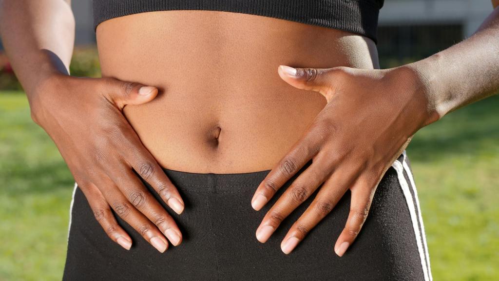 Close-up of a person’s hands resting on their stomach, symbolising gut health, digestion, or body awareness.